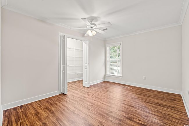 Unfurnished bedroom featuring crown molding, wood finished floors, a closet, a spacious closet, and a ceiling fan | Image 15