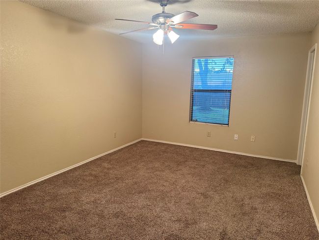 Unfurnished room featuring a textured ceiling, dark colored carpet, baseboards, and a ceiling fan | Image 5