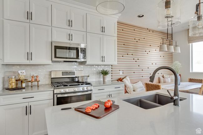 Kitchen featuring appliances with stainless steel finishes, light countertops, decorative backsplash, white cabinetry, and recessed lighting | Image 34