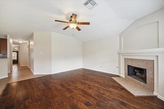 This inviting living room is the heart of the home, seamlessly flowing into the kitchen and dining area for effortless everyday living and entertaining. Warm engineered wood flooring adds charm underfoot, while the simple gas log fireplace anchors the space with cozy elegance. | Image 7