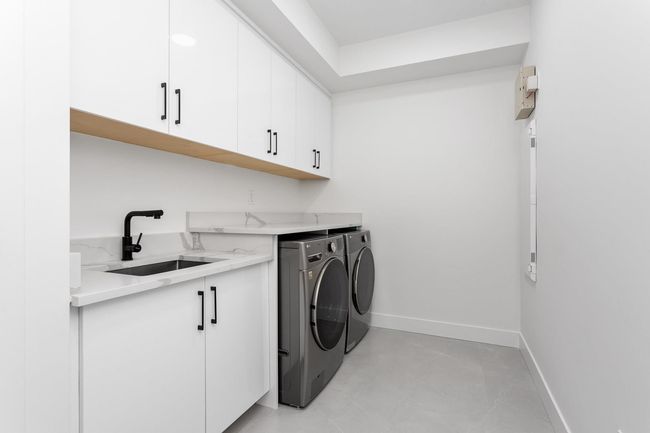 Washroom featuring baseboards, cabinet space, independent washer and dryer, and a sink | Image 28
