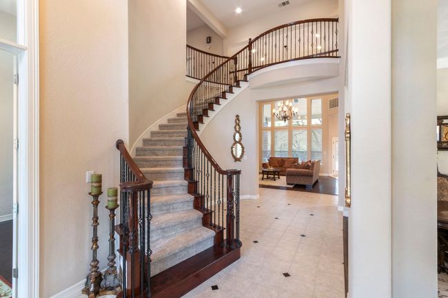 Tiled foyer entrance featuring baseboards, a high ceiling, stairway, and a chandelier | Image 6