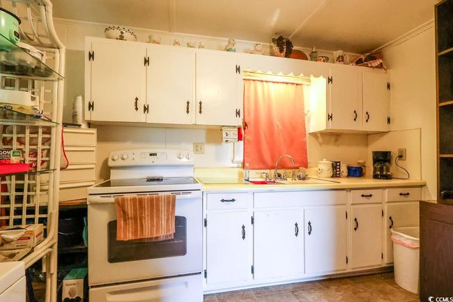 Kitchen featuring white electric range, a sink, light countertops, and white cabinetry | Image 27