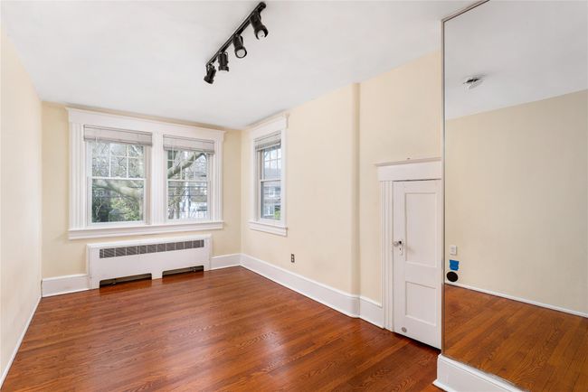 Unfurnished room with baseboards, wood finished floors, rail lighting, and radiator | Image 13
