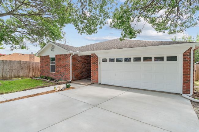 Ranch-style house with brick siding, concrete driveway, a garage, and roof with shingles | Image 5