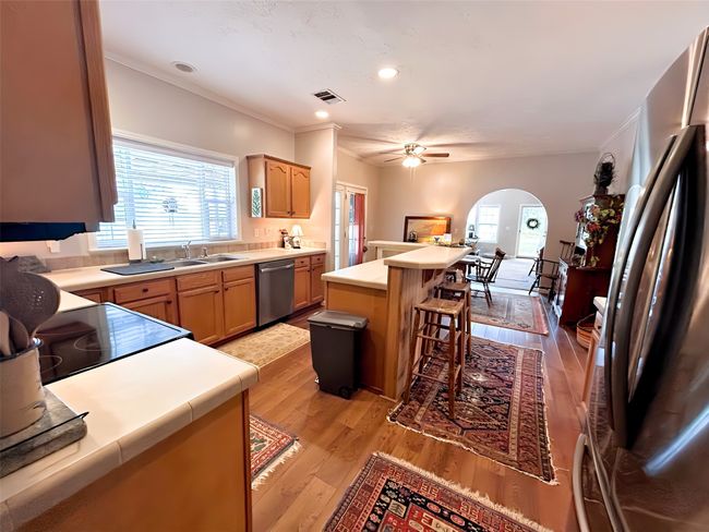 Kitchen with visible vents, a kitchen bar, stainless steel appliances, arched walkways, and light wood-type flooring | Image 16