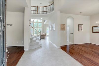 STEP INTO THIS INVITING ENTRYWAY FEATURING HIGH CEILINGS, ELEGANT TILE FLOORING, AND A GRAND STAIRCASE WITH AN OPEN LAYOUT THAT LEADS INTO A LIGHT-FILLED LIVING AREA. | Image 3