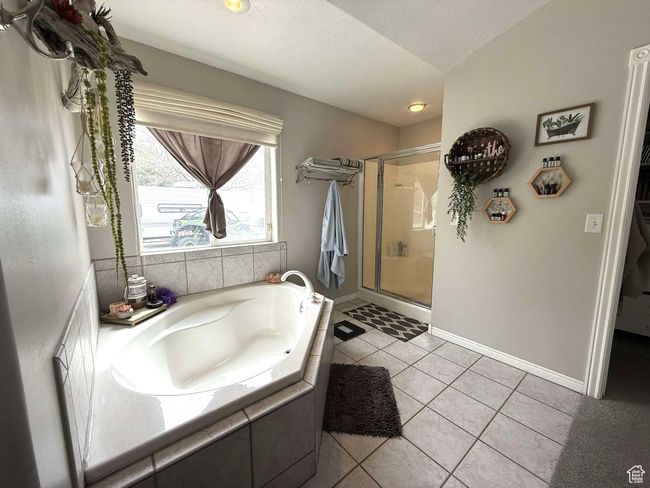 Bathroom featuring a stall shower, a garden tub, baseboards, and tile patterned flooring | Image 36
