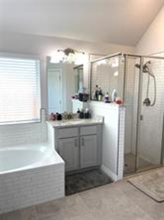 Bathroom with vanity, a bath, a stall shower, tile patterned flooring, and vaulted ceiling | Image 9