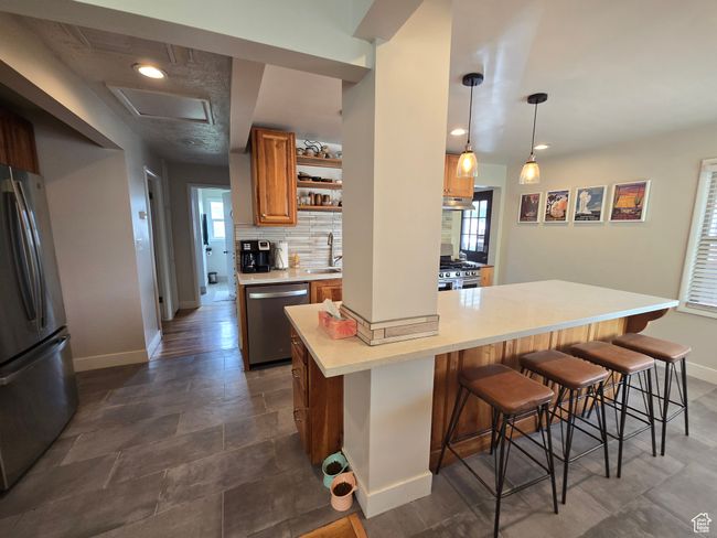 Kitchen with a sink, a breakfast bar area, stainless steel appliances, and baseboards | Image 16