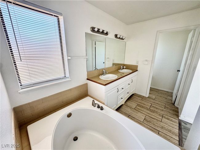 Bathroom with double vanity, wood finish floors, and a bath | Image 20