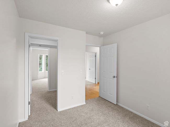 Unfurnished bedroom featuring light carpet, baseboards, and a textured ceiling | Image 14