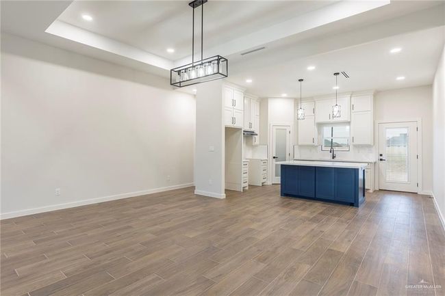 Kitchen with pendant lighting, white cabinetry, blue cabinetry, and a kitchen island | Image 8