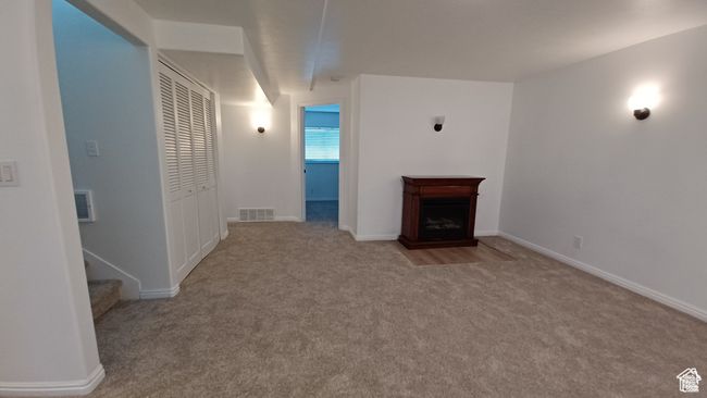 Unfurnished living room with carpet floors, a fireplace, and stairs | Image 25