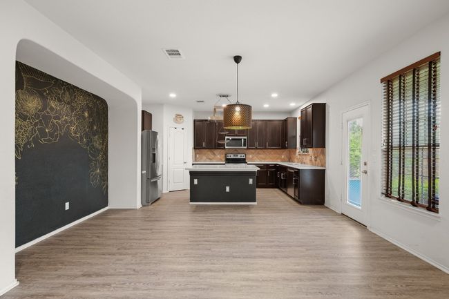 Kitchen featuring dark brown cabinets, light countertops, stainless steel appliances, decorative backsplash, and visible vents | Image 21