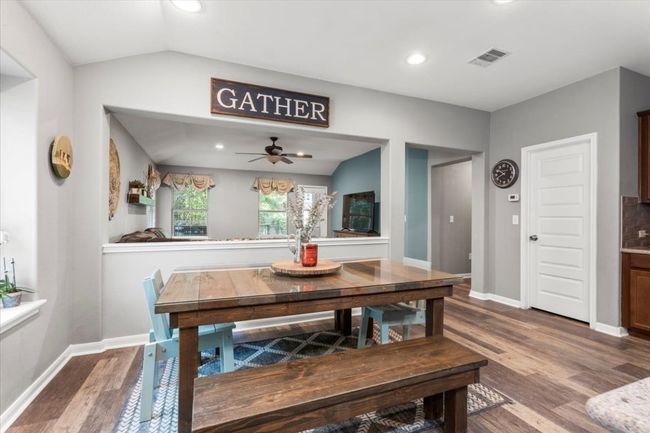 Dining room featuring wood laminate floors, a ceiling fan, baseboards, lofted ceiling, and recessed lighting | Image 12