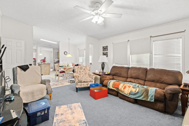 Carpeted living room featuring a textured ceiling and ceiling fan | Image 4