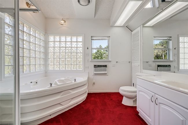 Down the hall is the full bath with frosted glassblock windows, whirlpool tub, separate shower, and ample natural light | Image 18