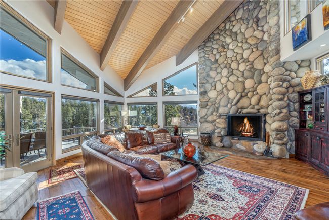 Living room with wood-type flooring, beamed ceiling, a stone fireplace, high vaulted ceiling, and wooden ceiling | Image 10