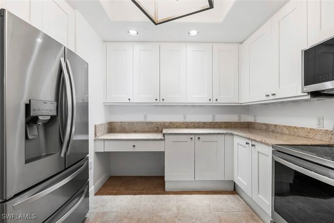 Kitchen with white cabinets, light stone counters, stainless steel appliances, and light tile patterned flooring | Image 34