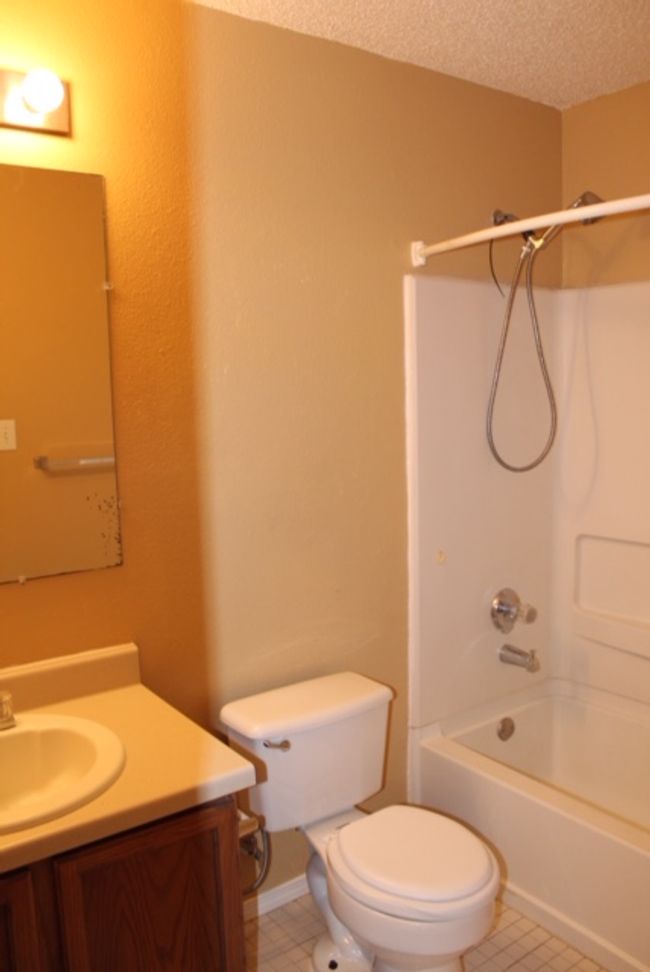 Bathroom with toilet, vanity, shower / washtub combination, a textured ceiling, and tile patterned flooring | Image 10