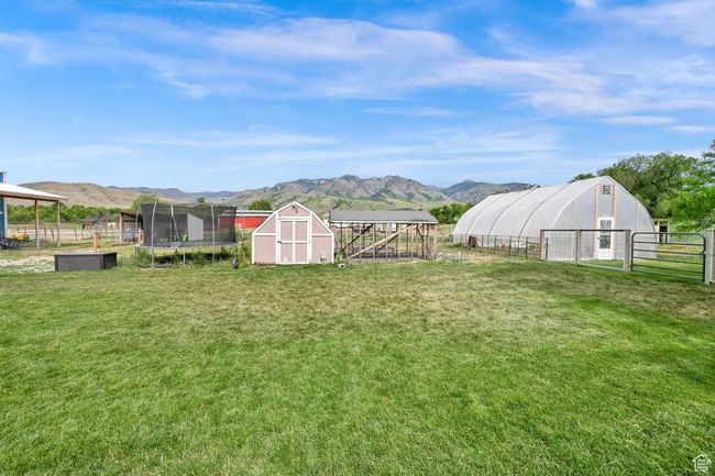 View of yard featuring a mountain view, a shed, an exterior structure, and a trampoline | Image 58
