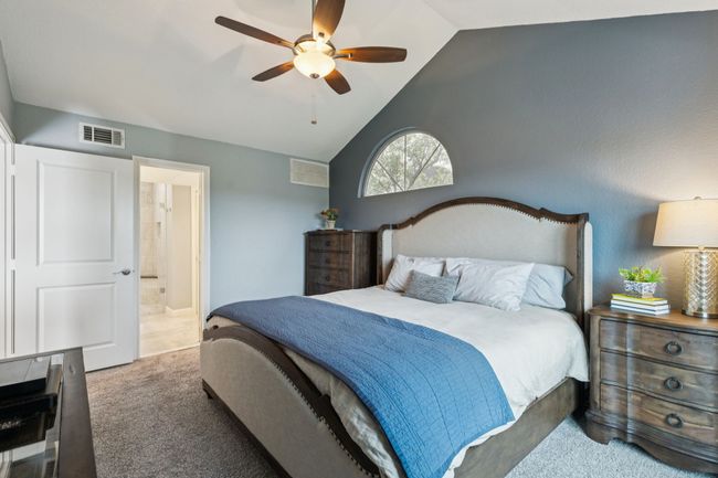 Carpeted bedroom featuring vaulted ceiling, ensuite bath, and a ceiling fan | Image 19