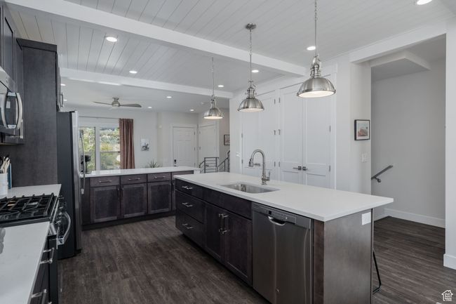 Kitchen with appliances with stainless steel finishes, a sink, dark wood finished floors, a kitchen island with sink, and light countertops | Image 9