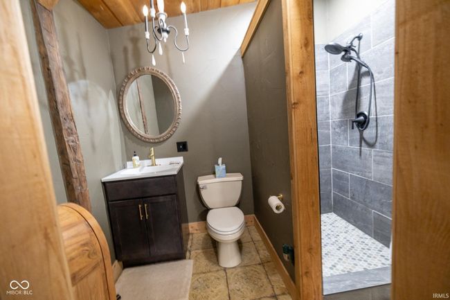 full bathroom with a tile shower, an inviting chandelier, vanity, toilet, and tile patterned floors | Image 11