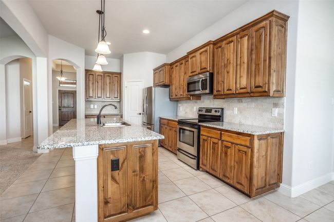 Kitchen with stainless steel appliances, light tile patterned flooring, arched walkways, decorative backsplash, and recessed lighting | Image 18