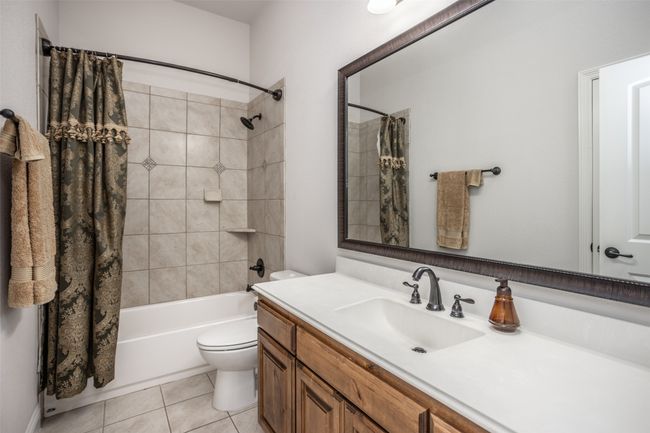 Bathroom with vanity, shower / bath combination with curtain, and tile patterned flooring | Image 32