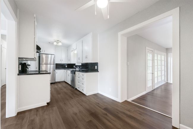 Kitchen featuring appliances with stainless steel finishes, dark countertops, dark wood-style flooring, and white cabinetry | Image 33