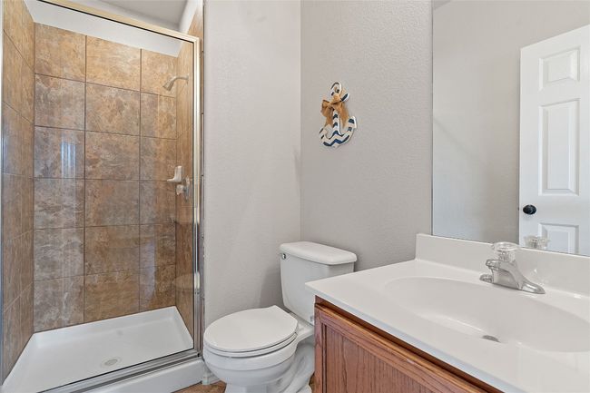 Bathroom featuring toilet, vanity, a textured wall, and a shower stall | Image 19