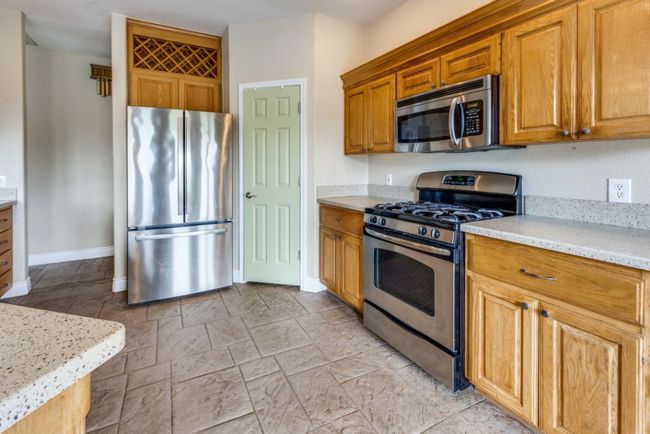 Kitchen featuring brown cabinets, light stone countertops, baseboards, and stainless steel appliances | Image 9