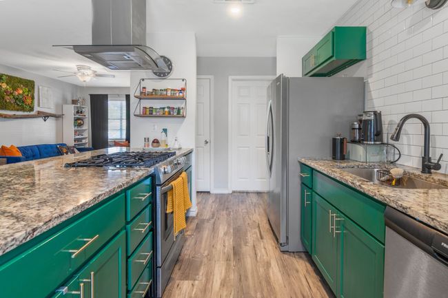 Kitchen featuring appliances with stainless steel finishes, a sink, island exhaust hood, a ceiling fan, and green cabinets | Image 15