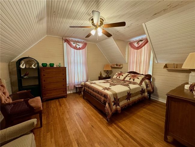 Bedroom with hardwood / wood-style floors, wooden ceiling, vaulted ceiling, a ceiling fan, and wooden walls | Image 30