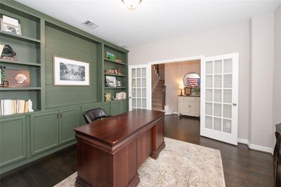 A spacious and elegantly appointed home office featuring custom built-in bookshelves and french doors. This room offers a sophisticated working environment or additional flex space with a classic aesthetic. | Image 3