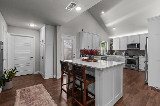 Kitchen featuring appliances with stainless steel finishes, tasteful backsplash, white cabinets, and high vaulted ceiling | Image 9