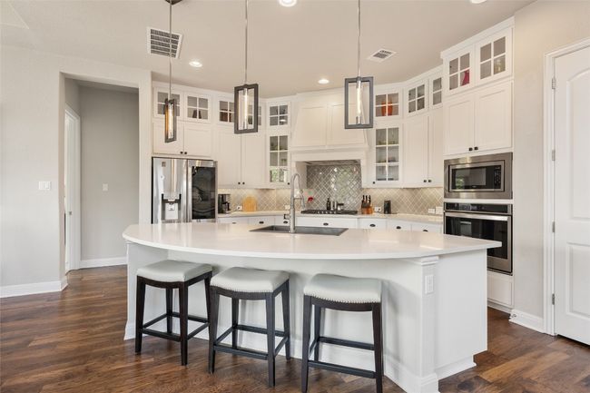 Kitchen featuring stainless steel appliances, decorative backsplash, dark wood-type flooring, recessed lighting, and light countertops | Image 13