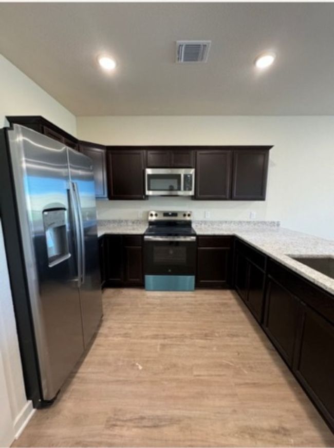 Kitchen featuring stainless steel appliances, light wood finished floors, dark brown cabinetry, recessed lighting, and a sink | Image 4