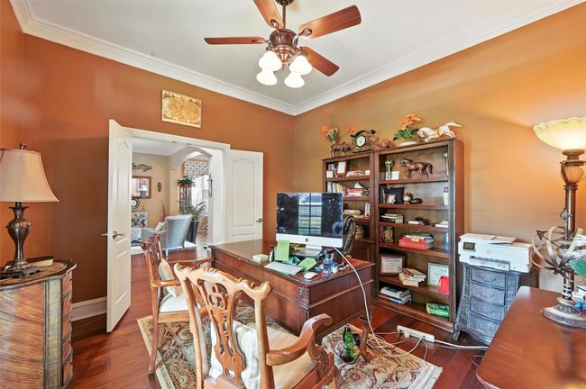 Home office with wood-type flooring, arched walkways, a ceiling fan, and crown molding | Image 25
