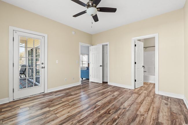 Unfurnished bedroom featuring access to exterior, a ceiling fan, wood finished floors, ensuite bath, and baseboards | Image 12