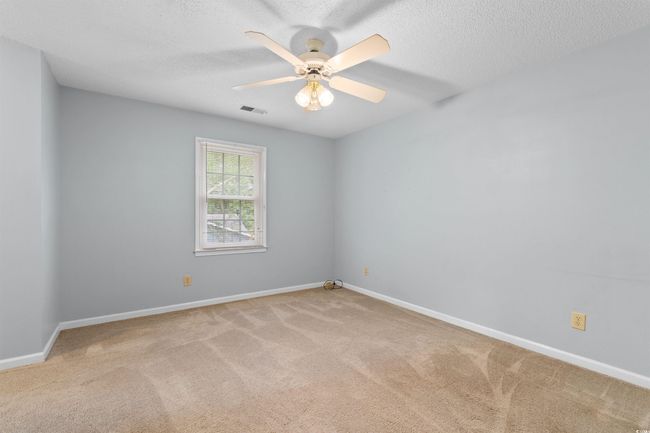 Carpeted empty room with ceiling fan and a textured ceiling | Image 18