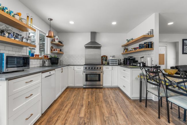 Kitchen featuring open shelves, stainless steel appliances, dark countertops, and wall chimney exhaust hood | Image 14
