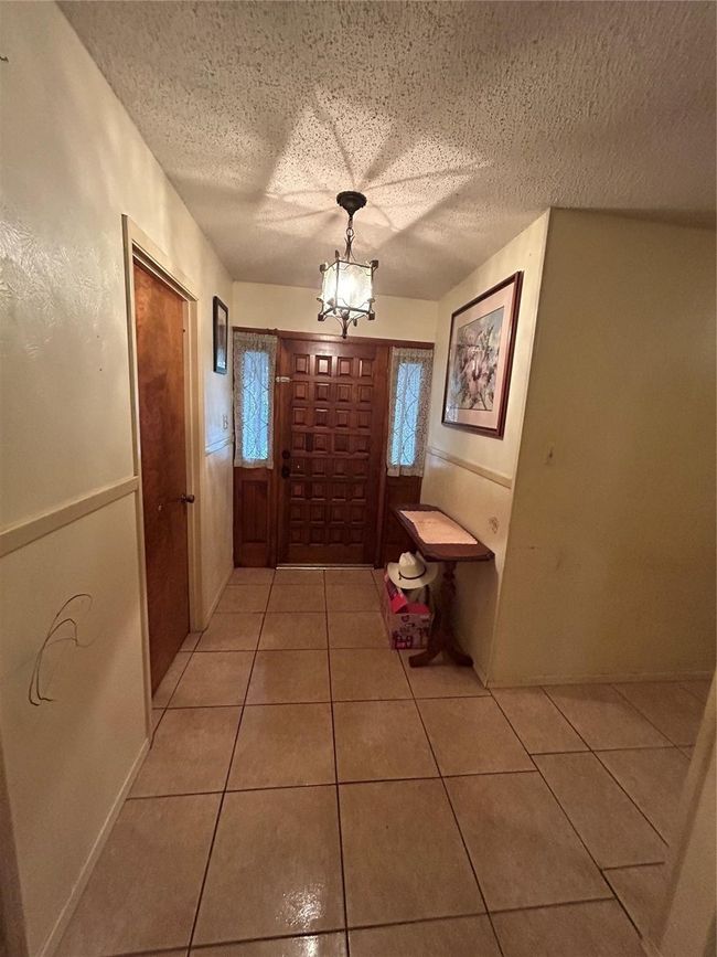Doorway to outside with light tile patterned flooring, a textured ceiling, and an inviting chandelier | Image 4