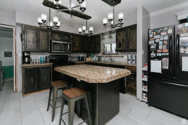 Kitchen with a chandelier, a textured ceiling, a sink, and black appliances | Image 10