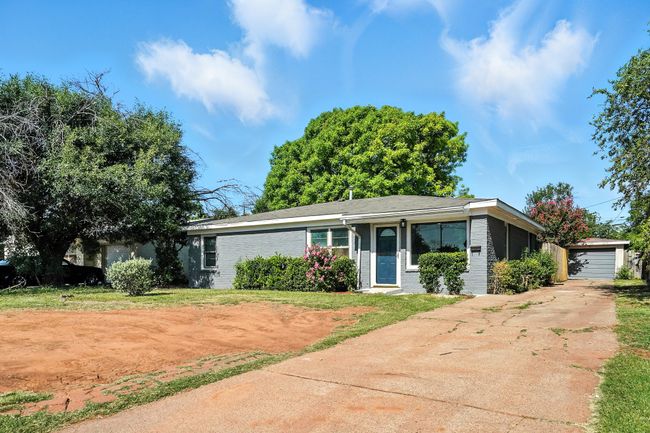 View of front of property featuring driveway, brick siding, an outdoor structure, and a garage | Image 28