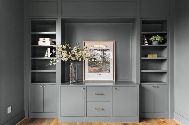 This moody office features oversized windows that allow soft, natural light to pour in, creating a balanced, inviting atmosphere. Custom bookshelves line the walls, offering both style and storage, while a "hidden" closet seamlessly blends into the design, adding an element of surprise and functionality. | Image 27