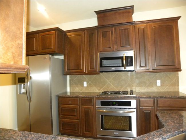 Kitchen featuring appliances with stainless steel finishes, tasteful backsplash, and dark stone countertops | Image 19