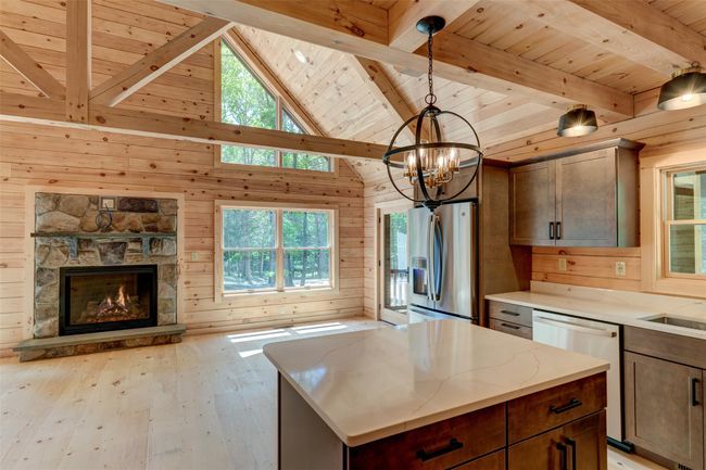 Kitchen featuring stainless steel appliances, wood ceiling with exposed beams, wooden walls, plenty of natural light, and a chandelier | Image 16